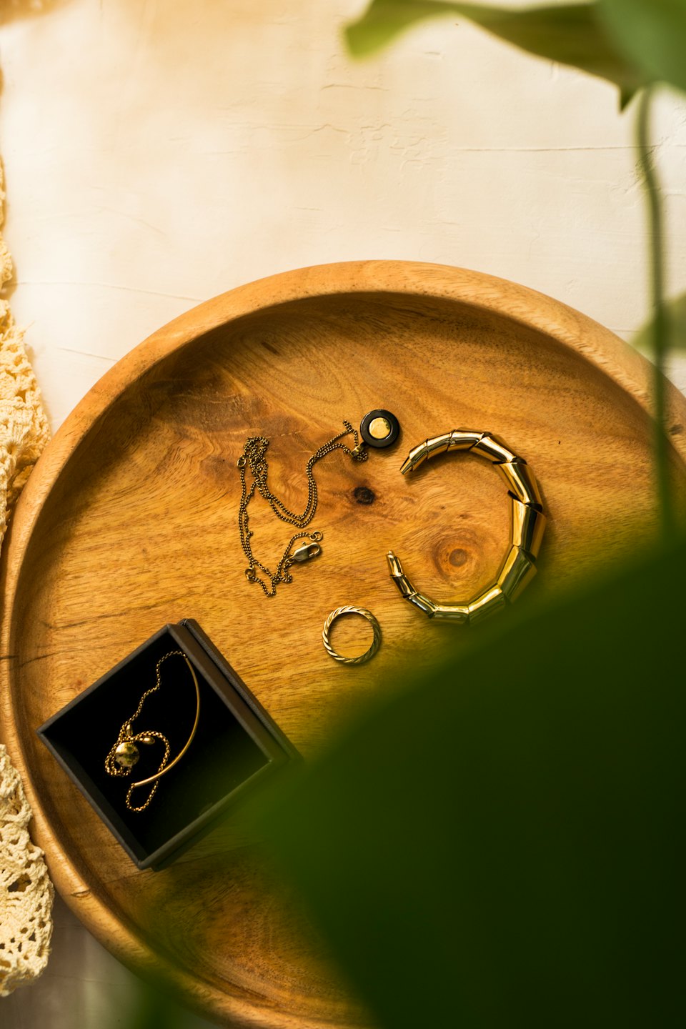 Bijoux en or sur un plateau rond en bois.